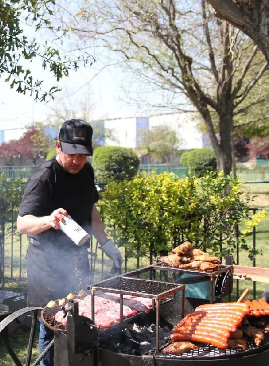 Parrillero sazonando cortes sobre la parrilla